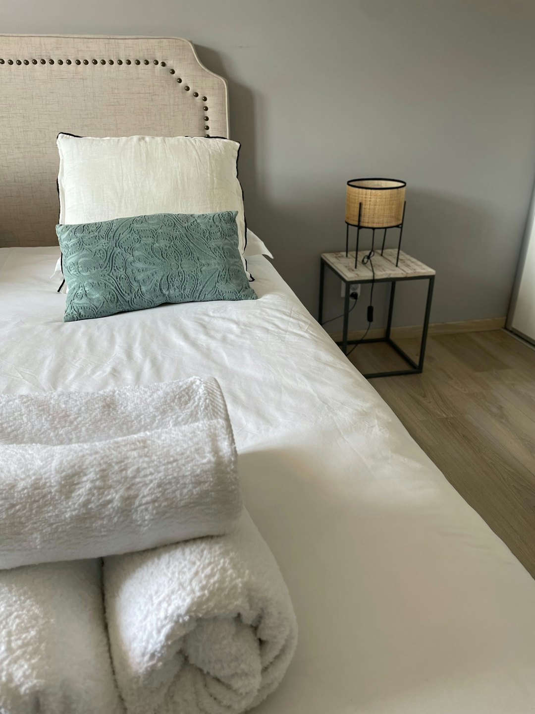 A made bed with towels sits beside a small lamp.