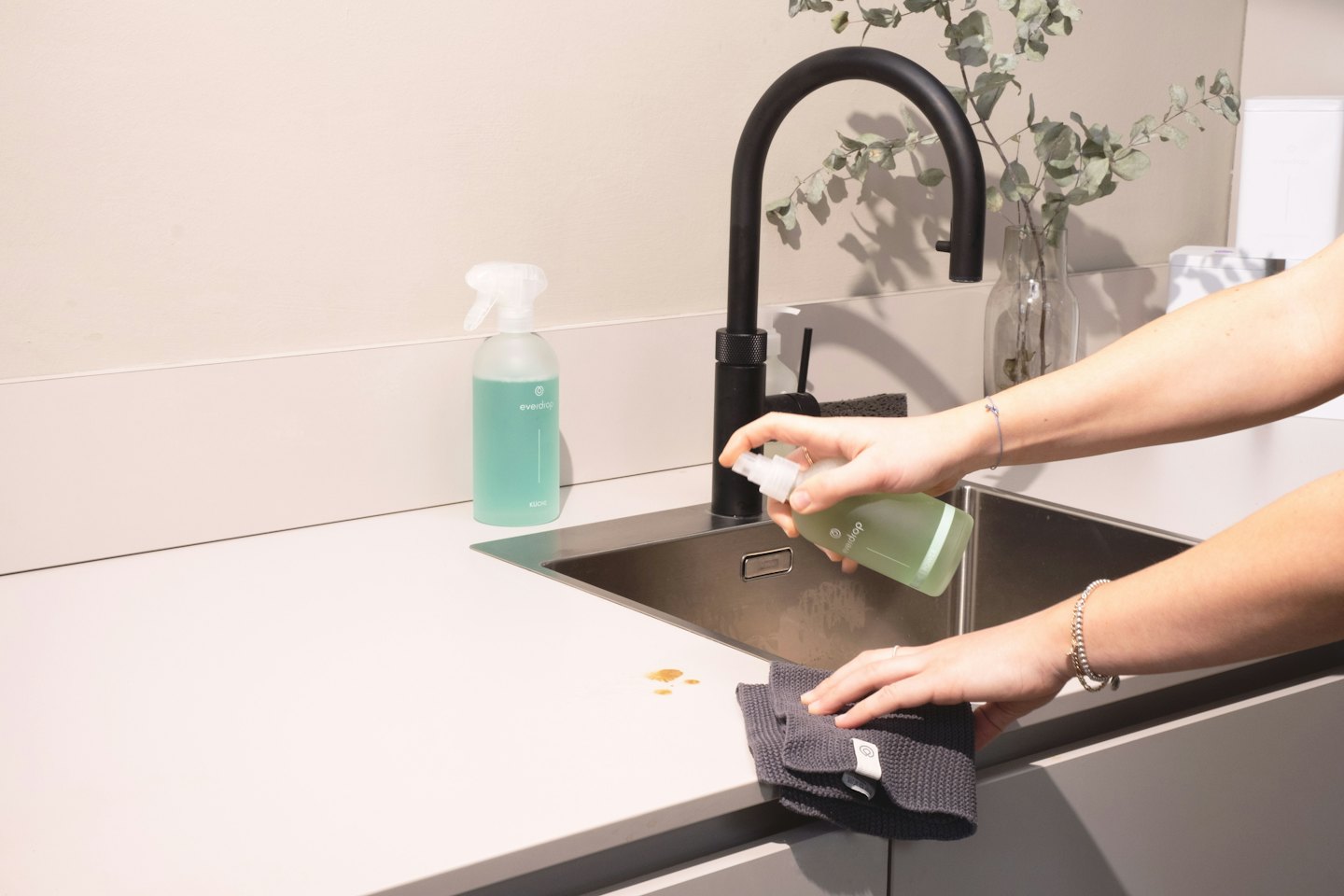 Hands wiping a spill on a modern kitchen counter.