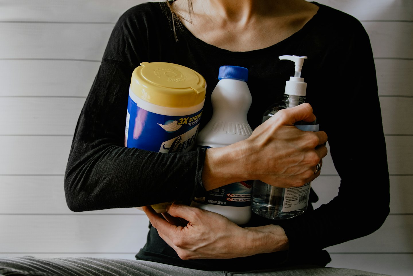 Person holding cleaning supplies like wipes and sanitizer.